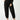 A person is standing, dressed in a black long-sleeve top and the "Sahara Tapered Pant Black" from the Inclusive Collection by Sanctuary Clothing. Their hands are in their pockets, and they are wearing black ballet flats. The background is a plain, light color.