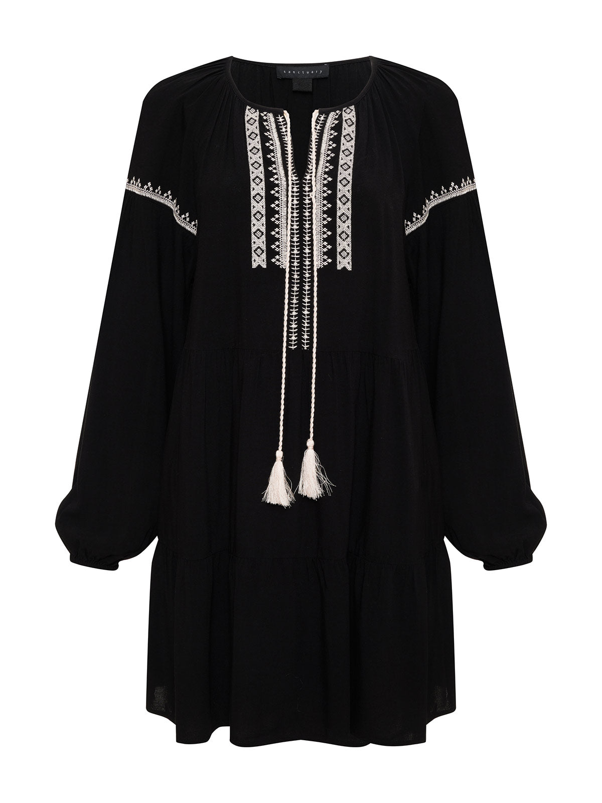 The Embroidered Dress Black by Sanctuary Clothing features white embroidery along the neckline, down the front, and across the chest. It has a tie-up detail with two white tassels and offers a relaxed, loose fit. The slightly puffed sleeves are gathered at the cuffs for added charm.