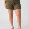 A person wearing the Rebel Short Hiker Green Inclusive Collection cargo shorts by Sanctuary Clothing, featuring a double-button and zip closure, and a tucked-in green t-shirt. They are also wearing tan flat sandals with a gold accent on the strap. The background is plain, showcasing the outfit.