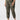 A person is wearing the Rebel Pant Hiker Camo from Sanctuary Clothing's Inclusive Collection, featuring elasticated cuffs, paired with a black top. They are also sporting white sneakers with a light-colored "V" logo on the side. The person is standing against a plain white background.