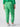 A person is wearing the Rebel Pant in Green Goddess from the Inclusive Collection by Sanctuary Clothing. The bright green cargo pants feature multiple pockets and elastic cuffs at the ankles. They are also wearing a green long-sleeve top and white sneakers. The image shows the person from the back, highlighting the fit and style of these distinctive pants.