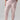 Person wearing Rebel Pant Washed Pink No 3 Inclusive Collection by Sanctuary Clothing with ankle cuffs and a black sweater featuring light pink flowers. They are also wearing beige ballet flats. The person's hands are in the pants' pockets. The background is plain and light gray.