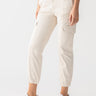 A person is wearing the Rebel Pant Crystal Stone from Sanctuary Clothing, which are light beige cargo pants with multiple pockets and cinched ankles. The person is also sporting white sneakers with a subtle pattern. Only the lower half of the body is visible, set against a neutral background.