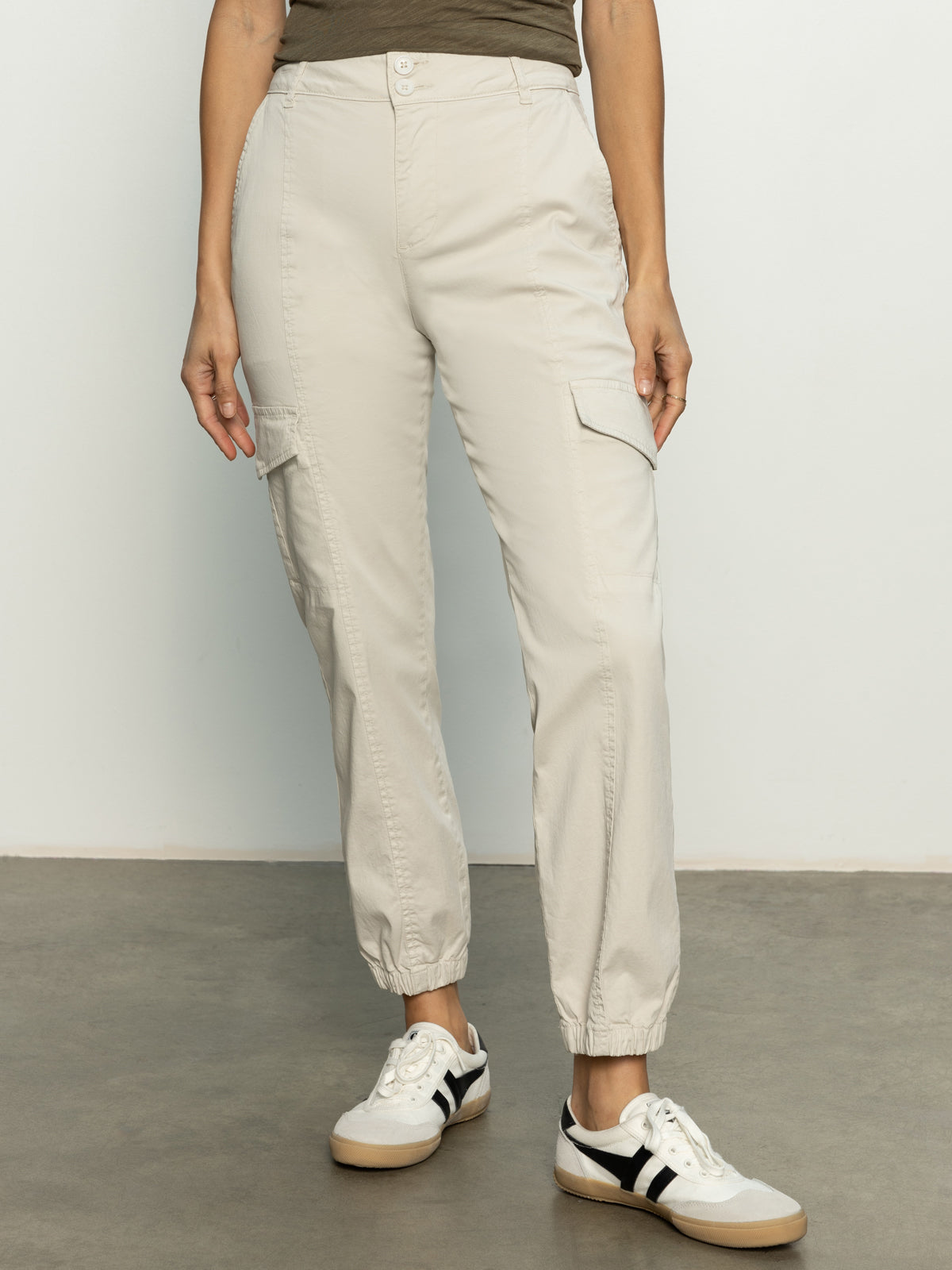 A person in Sanctuary Clothing's rebel pant pumice stone stands on a gray floor against a white background, paired with black and white sneakers.