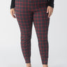 A person wearing the Sanctuary Clothing Runway Legging Mars Red Check from the Inclusive Collection stands against a plain background. They are also wearing a black textured long-sleeve top and black flats, with their arms resting at their sides.