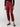 A person stands against a plain background wearing the Classy Cargo Trouser Garnet by Sanctuary Clothing, paired with a matching belt. They are also wearing a black long-sleeved top and black flat shoes with buckles. The photo is cropped to show only the body from the shoulders down.