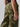 A person is wearing the Cargo Parachute Pant Renew Camo by Sanctuary Clothing and a black top. Their arm is relaxed by their side, displaying a simple gold ring on one finger. The image emphasizes the lower torso and upper legs, showcasing the intricate design and pattern of the camouflage pants.