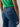 A person wearing Level Up Cargo Pant Oasis from Sanctuary Clothing and a green top, photographed from the back. The cargo pants have two back pockets with flaps and stitching details. The background is plain and light-colored.