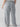 A person wearing the Doheny Cargo Eucalyptus Inclusive Collection pants by Sanctuary Clothing, which are light grey with wide legs and large pockets on the sides and back, is facing away from the camera. The person is also wearing a white shirt. The background is plain and neutral.