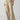 The individual is adorned in Sanctuary Clothing's Reissue 90s Sash Extended Marble Beige high-waisted, wide-leg trousers with a tie belt, paired with a green top. They are standing confidently with hands in pockets, showcasing the casual and comfortable ensemble, completed by light-colored flat shoes.