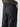 A person wearing the Sanctuary Clothing Cinched Nylon Cargo Pants in black, with their hand in the large side pocket. The pants include back welt pockets and spacious side pockets. The individual is also dressed in a dark green long-sleeve shirt.