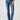 A person wears Sanctuary Clothing's Sculpted Hayden Bootcut Lucky Streak jeans, which feature front pockets and visible stitching. They pair the high-waisted blue jeans with a beige and black striped sweater, completing the look with black pointed-toe shoes. The background is light gray.