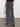 A person wearing Sanctuary Clothing's Speed Denim Cargo Odyssey stands against a neutral background. The gray wide-leg cargo jeans feature multiple side pockets and have a faded, slightly worn appearance. The person's hands are casually tucked into the front pockets.