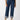 A person wearing the Luna Cuffed Denim Pant Solstice from Sanctuary Clothing, a pair of high-waisted blue jeans with cuffed hems and button details, is paired with an untucked blue shirt and beige ankle boots against a plain white background.