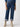 A person wearing the Luna Cuffed Denim Pant Solstice from Sanctuary Clothing, a pair of high-waisted blue jeans with cuffed hems and button details, is paired with an untucked blue shirt and beige ankle boots against a plain white background.