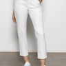 A person is wearing Sanctuary Clothing's sculpted Hayden straight crop pants in brilliant white, paired with white sneakers featuring pale yellow accents. They stand against a plain background, one hand in their pocket, and they're also in a light blue top.