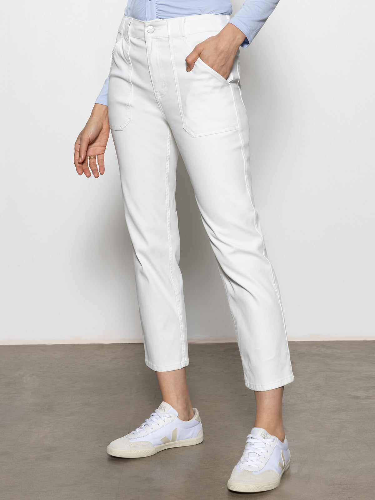 Person wearing Sanctuary Clothing's sculpted hayden straight crop pant in brilliant white and a light blue top with white sneakers, standing against a neutral background. Their face is not visible.