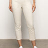 A person is standing on a grey floor wearing Sanctuary Clothing’s sculpted hayden straight crop pants in light oat paired with white sneakers. The pants feature front seam details and large pockets, while the top is black but only partially visible. The background is plain white.