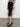 A person stands against a white wall wearing Sanctuary Clothing's clipper ponte capri pant in black and black woven ballet flats, with only the lower half of their body visible.