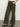 A person wearing the Sanctuary Clothing rosette army pant in kalamata, featuring floral embroidery on the side, stands against a plain background. They pair these olive green wide-leg pants with black sandals.