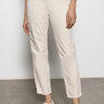 A person stands against a neutral background wearing Sanctuary Clothing's trade maker pant in light oat. Their upper torso isn't visible; one hand rests by their side while the other touches their pocket. They pair the pants with white woven flats.