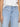 A person wearing Sanctuary Clothing's "Voyage Full Length Pant" in the color Wishful Thinking is paired with a white top. The light blue jeans feature wide belt loops and two horizontal front pockets, and the person stands with their arms relaxed at their sides.