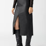 A person wearing a black lace long-sleeve top is paired with the Long Coated Skirt Black from Sanctuary Clothing, a faux leather midi skirt featuring a front slit. They are also wearing knee-high black boots with a pointed toe and slim heels. The background is plain white.