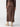 A person is seen from the back wearing the Sanctuary Clothing "Classy Cargo Skirt Brown Sugar," a long brown satin skirt with a high waist and side pockets. They are also wearing a dark brown, long-sleeved top and light beige heeled boots. The background is plain and light-colored.