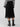 A person wearing the Tulle Pleated Midi Skirt Black by Sanctuary Clothing stands with their back to the camera. They also wear a black and white striped sweater and black ankle boots, all set against a plain background.