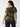 A person with long, dark hair stands with their back to the camera, wearing The Perfect Tee Hiker Camo Inclusive Collection by Sanctuary Clothing and dark pants. They have hoop earrings and are posed against a plain white background.