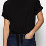 A person wearing Sanctuary Clothing's all day tie tee black from the inclusive collection, paired with blue jeans, has one hand in their pocket and is standing against a plain white background.