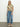 A woman models the Sanctuary Clothing "the perfect tee precious camo," paired with blue jeans against a white backdrop. She stands on a grey floor in light-colored woven slip-on shoes, exuding a laid-back and comfortable vibe with her relaxed stance.