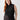 A person with long red hair is standing against a plain background, dressed in the Sanctuary Clothing Shirred Neck Mesh Tank Black from the Inclusive Collection and dark pants. Their right hand is resting on their hip and they are looking at the camera with a neutral expression.