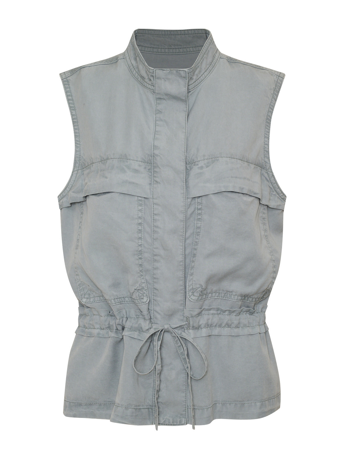 The Lora Surplus Vest Eucalyptus by Sanctuary Clothing is a sleeveless, light grey utility vest with a high collar. It features two large chest pockets, a drawstring waist, and a front zipper closure. The fabric appears to be lightweight and slightly worn for a casual, relaxed look.