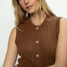 A woman with long blonde hair models the Sanctuary Clothing "pointelle shell sepia," a sleeveless brown knitted top with buttons, as she gazes neutrally at the camera against a plain, light-colored background.