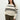 A person in a Sanctuary Clothing sporty stripe open knit sweater, featuring eco natural with black stripes from the inclusive collection, stands against a plain background. They have long brown hair and are wearing olive green pants, one hand in their pocket.