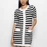 A woman wears the Sanctuary Clothing button front knitted dress in chalk and black stripe, featuring a round neckline, short sleeves, and front pockets. She stands against a plain white background.