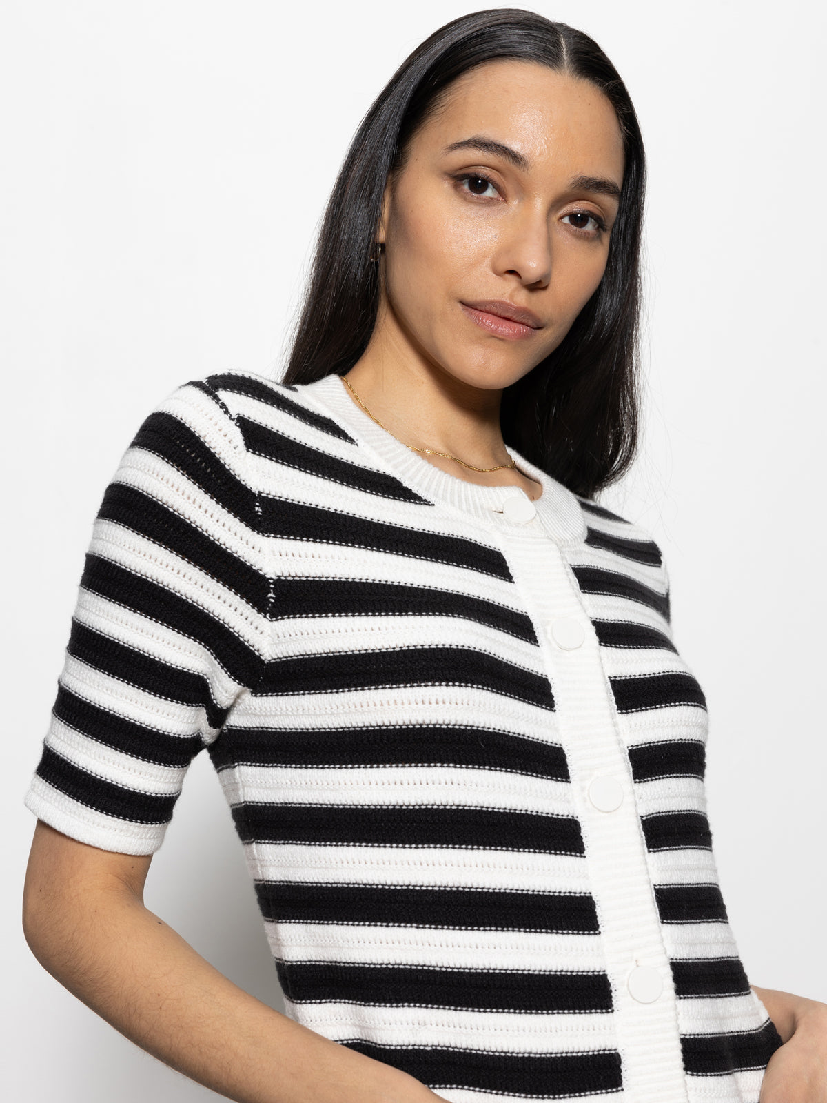 A person with long, dark hair is wearing Sanctuary Clothing's button front knitted dress in chalk and black stripe. They are standing against a plain white background, looking at the camera.