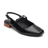 The Everly Slingback Flat Black by Sanctuary Clothing is a black leather shoe featuring a square toe, a narrow strap across the top with an adjustable buckle, and a small wooden heel. The design is minimalist and chic.