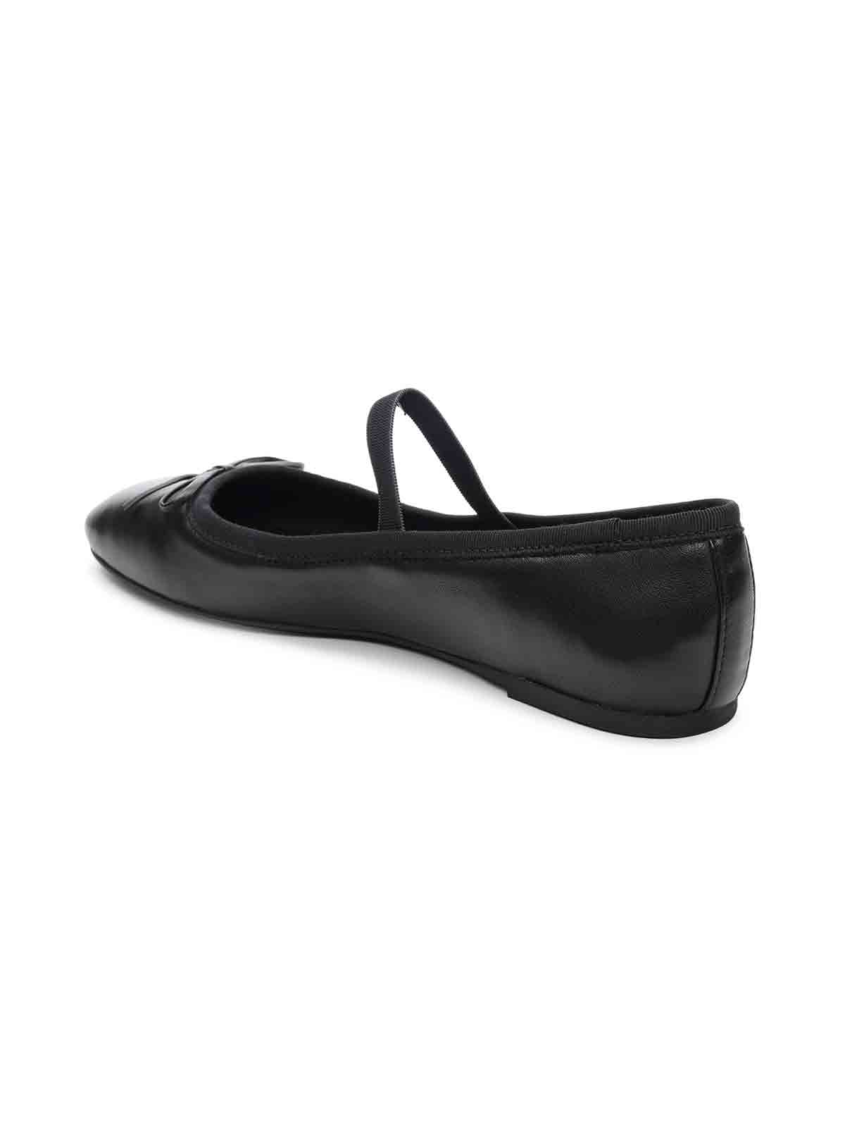 The "Facile Ballet Flat Black" by Sanctuary Clothing is showcased against a white backdrop. Crafted from a shiny material, this ballet flat features a pointed toe and an elastic strap across the midfoot. The shoe boasts a flat heel and exudes a simple yet elegant aesthetic.