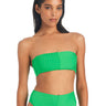 A woman is wearing the Refresh Rib Bandeau Bikini Top in Green Flare by Sanctuary Clothing, paired with high-waisted bikini bottoms. The bikini features a textured, ribbed design. She has long, dark hair that is slicked back and is standing against a plain white background, looking into the camera.