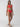 A person wearing the Sanctuary Clothing refresh rib double layer underwire bikini top in Mars Red poses against a plain background. They're standing confidently with one leg slightly forward, looking towards the camera with a slight smile, accessorized with black flip-flops.