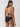 A woman dressed in Sanctuary Clothing's "sea crochet hipster bikini bottom black" poses with her back to the camera. The bikini has a textured design. She has long dark hair and is accessorized with small hoop earrings. The backdrop is a simple light gray.