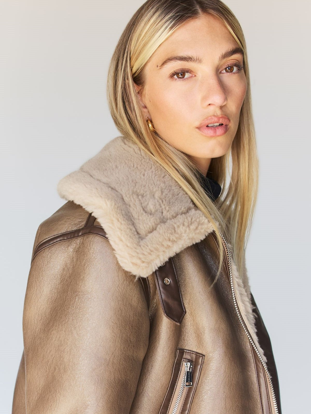 A person with long blonde hair is wearing the Zarina Shearling Coat in Mink Beige by Sanctuary Clothing. They are looking directly at the camera against a plain background.