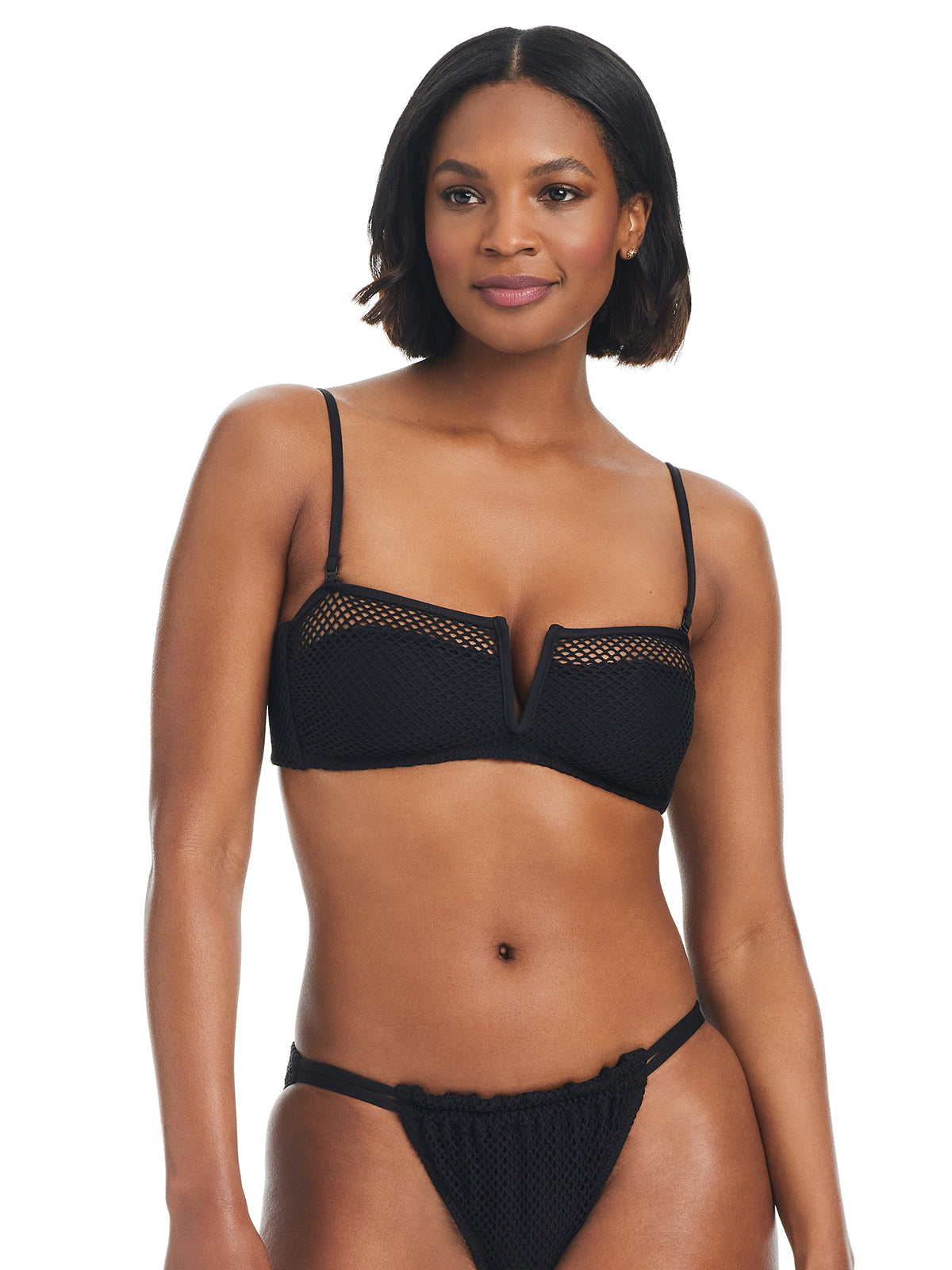 A woman with shoulder-length hair is wearing the Sanctuary Clothing V Wire Bandeau Bikini Top in black, complete with mesh details. The bikini top features a V-cutout neckline and is paired with matching bottoms. She is standing and smiling slightly.