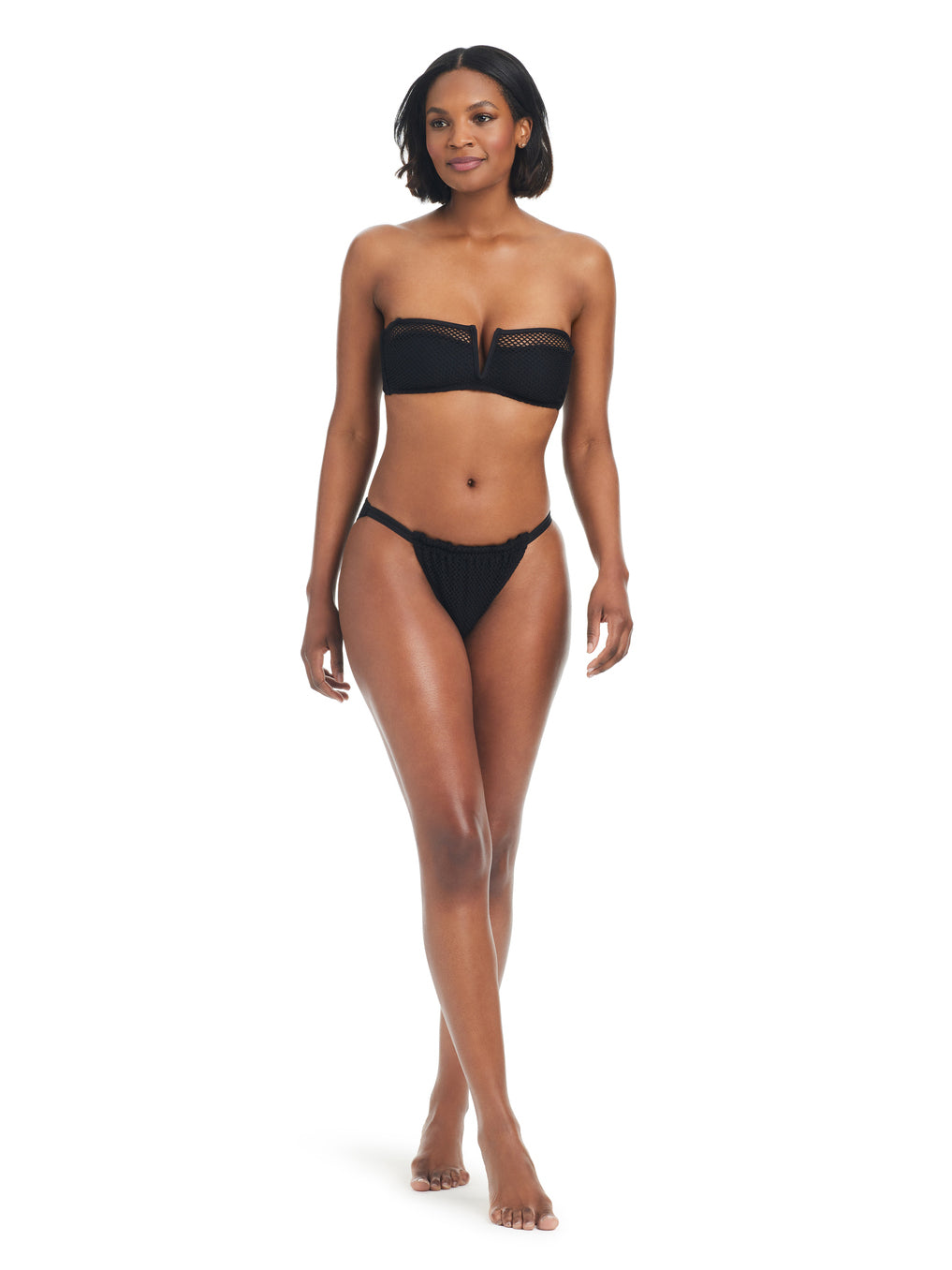 A woman with shoulder-length dark hair is posed against a white background. She is wearing a Sanctuary Clothing V Wire Bandeau Bikini Top in black and matching black bikini bottoms. She stands with a neutral expression, her arms relaxed by her sides.