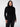 A person with medium-length dark hair is wearing the Essential Turtleneck Black from the Sanctuary Clothing Inclusive Collection and black jeans. They stand against a plain white background, looking directly at the camera with a confident and composed expression.